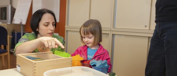 Frühförderin erklärt kleinem Mädchen die verschiedenen Bausteine